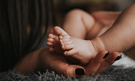 woman holding new boarn baby's feet in her hand