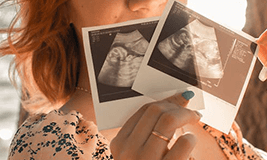 a mother holding two sonography pictures
