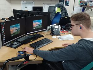 Dan sitting at a computer with two monitors, using the mouse