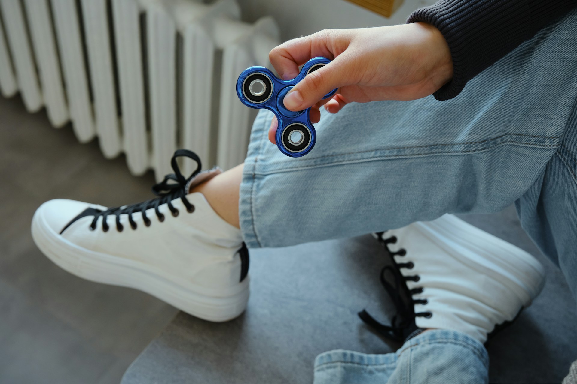 Close up view of teen with jeans and white boots, holding fidget spinner,