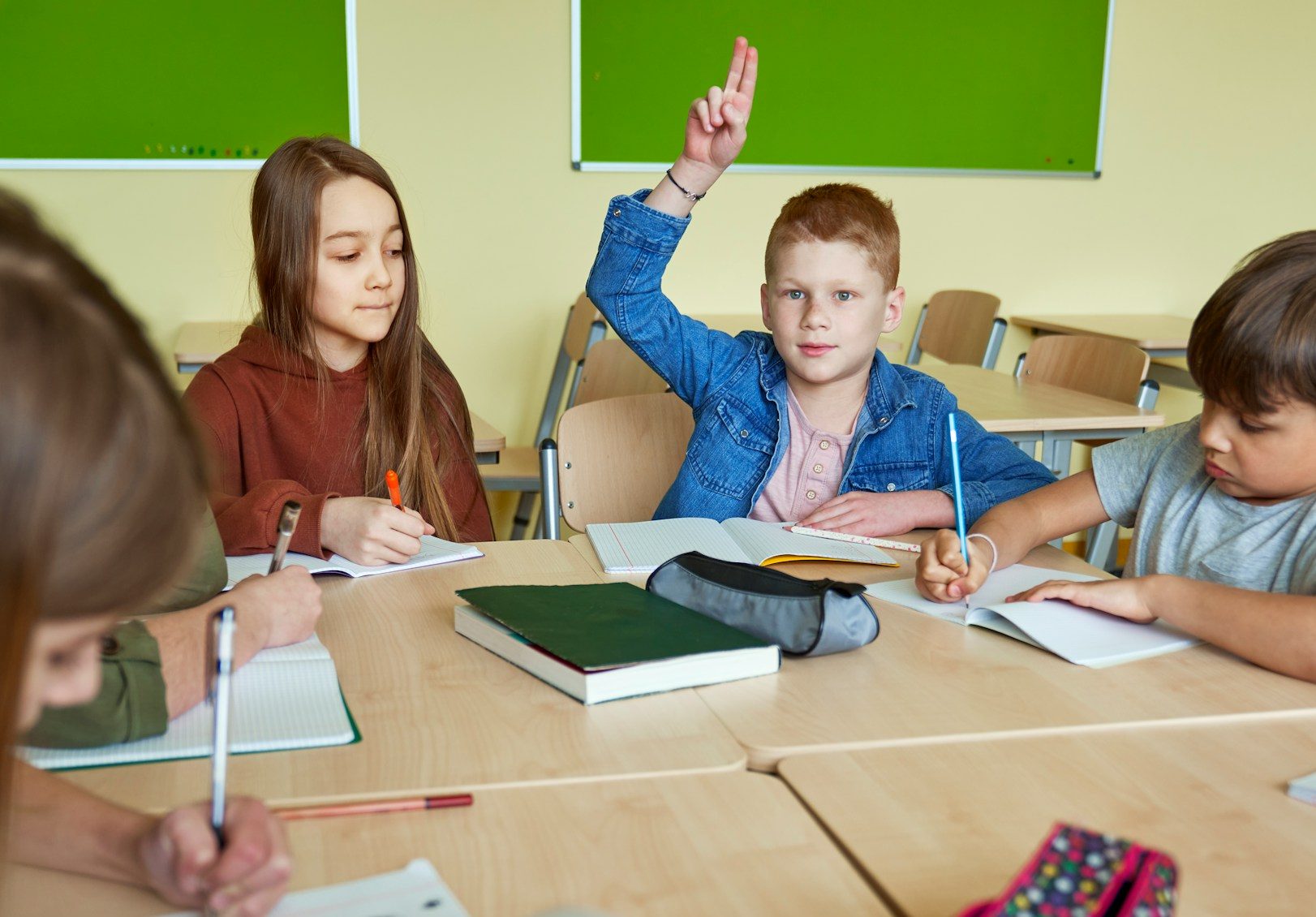 boy in classroom with hand raised