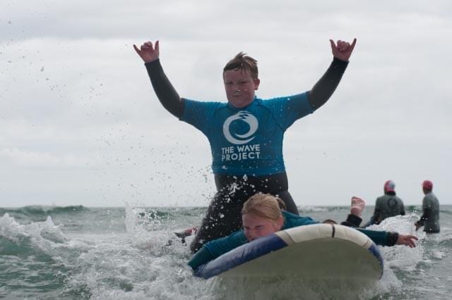 Two young people on a surf board, in the water